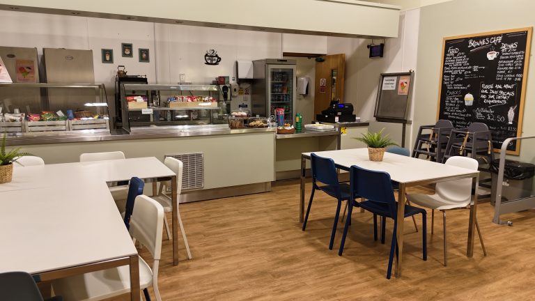 A room that is the cafe with tables, chairs and food counter.