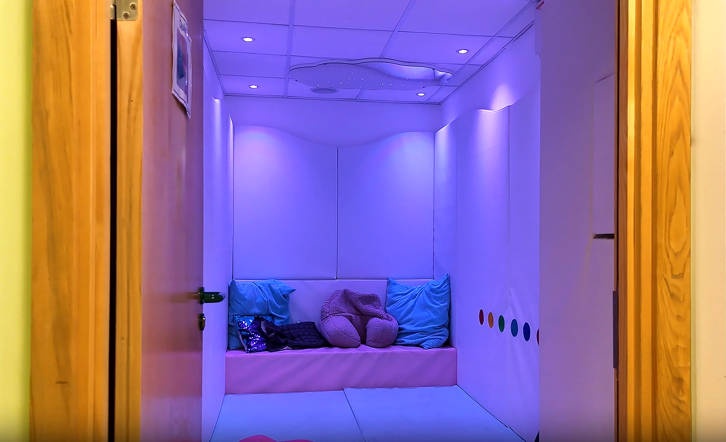 A room with padded walls and floor with purple lighting.
