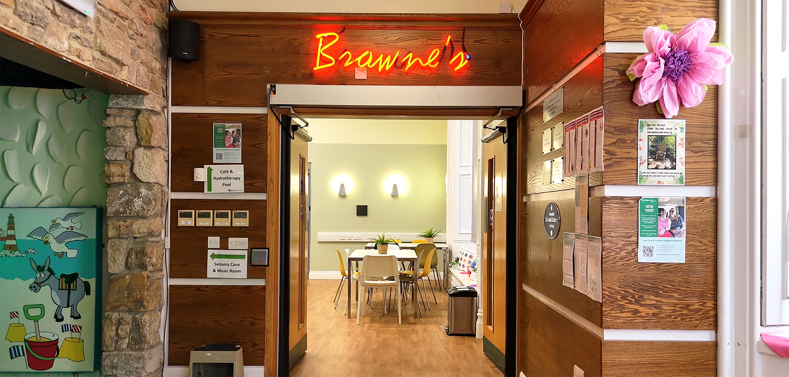 The entrance to a cafe with neon signs and wood panelling on the walls