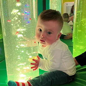 Little boy cuddling a light up glass tube filled with water and sensory toys