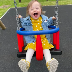 Little girl in a yellow dress sitting in a swing